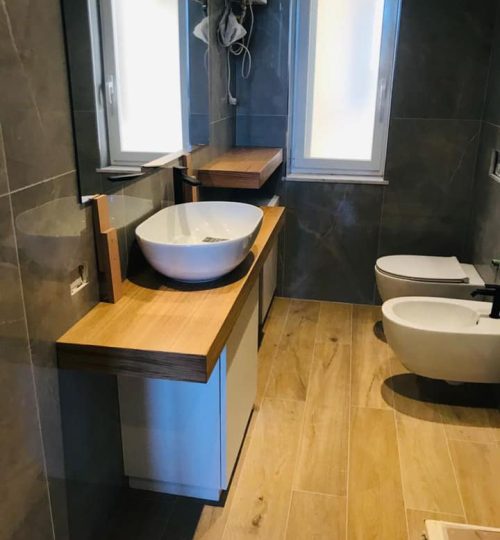 Bagno in stile contempraneo con effetto marmo in parerta e legno a pavimento presso abitazione privata di Corso Firenze, Genova